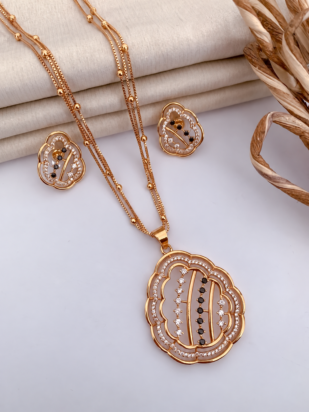 Gold floral pendant and matching studs with black and clear stone accents